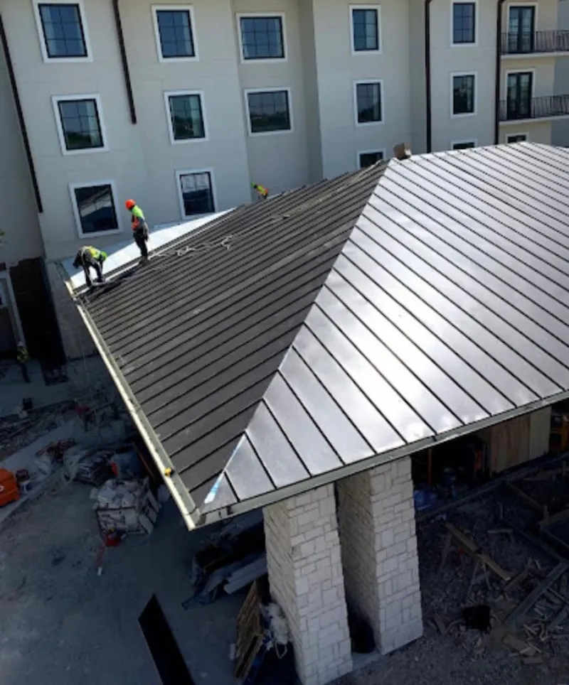 Crew installing standing seam metal roof panels on a commercial project in Pebble Creek